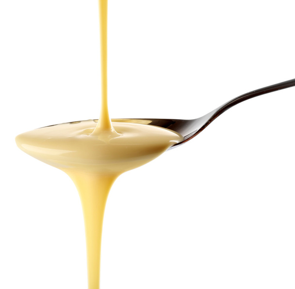 Condensed milk pouring from a spoon - Foto, Imagem