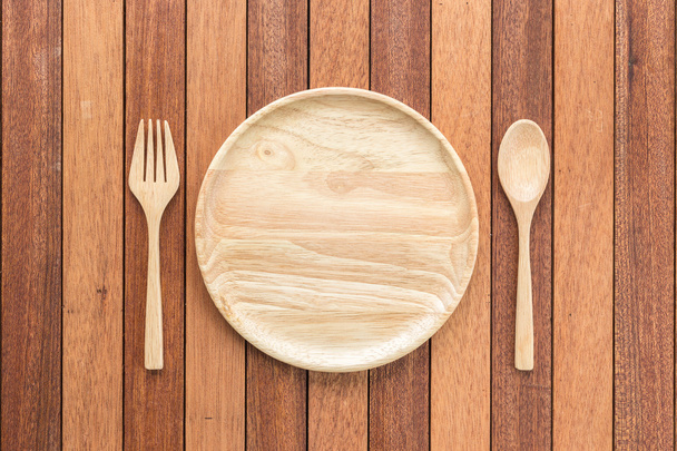 Empty wooden dish, fork and spoon on wooden table - Valokuva, kuva