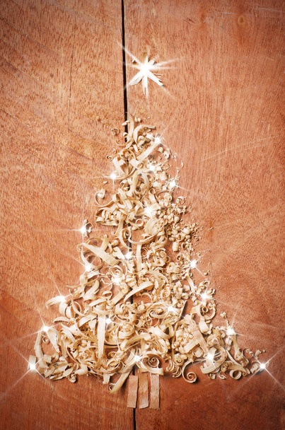 Eenvoudige kerstboom gerangschikt van zaagsel, houtspanen op houten achtergrond. - Foto, afbeelding