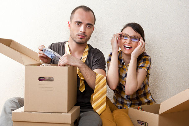 Молодая пара с коробками в новой квартире сидя на полу и планируя
 - Фото, изображение
