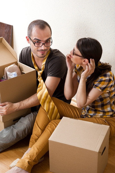 Casal jovem com caixas no novo apartamento sentado no chão e planejamento
 - Foto, Imagem