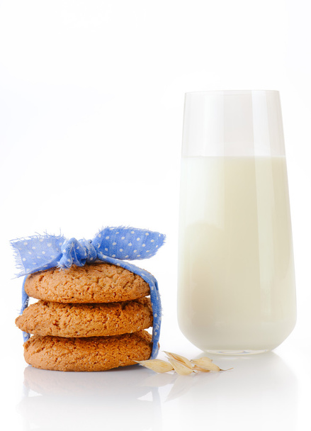 Three homemade oatmeal cookies tied with blue ribbon in small white polka dots, ear of oats and glass of milk - Fotoğraf, Görsel