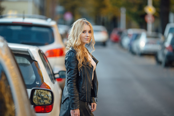 Pretty young woman walking on the street with cars - Zdjęcie, obraz