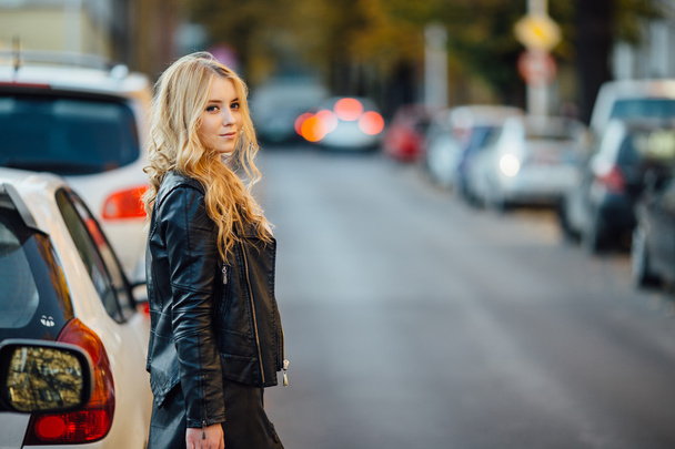 Pretty young woman walking on the street with cars - Foto, Bild