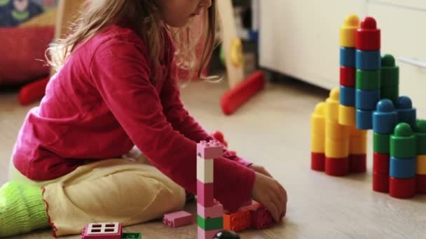 Cute little girl playing with toy blocks at home - Video