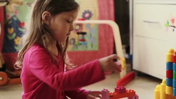 Cute little girl playing with toy blocks at home - Materiał filmowy, wideo
