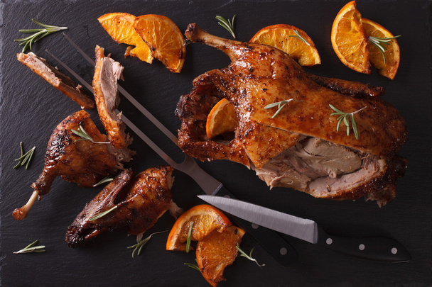 Cutting the roast duck and oranges on a slate board. Horizontal - Photo, Image