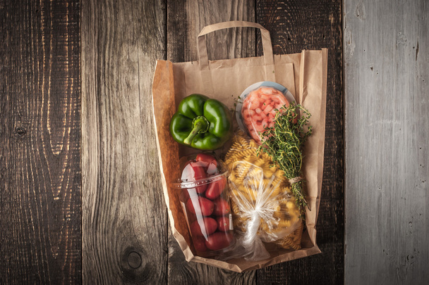 Food mix inside a paper bag on the wooden background horizontal - Photo, Image