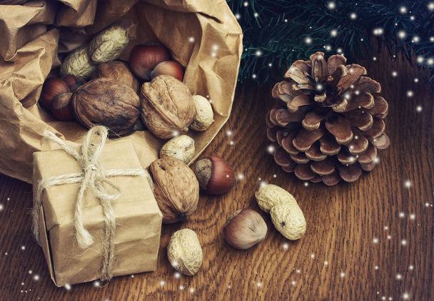 Christmas background with gift, peanuts, hazelnuts, walnuts - 写真・画像