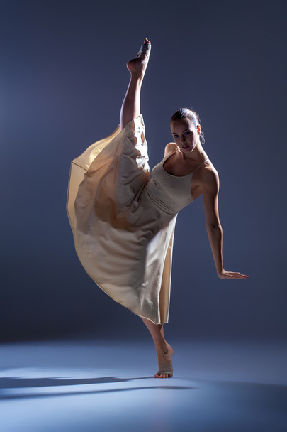 Young beautiful dancer in beige dress dancing on gray background - Zdjęcie, obraz