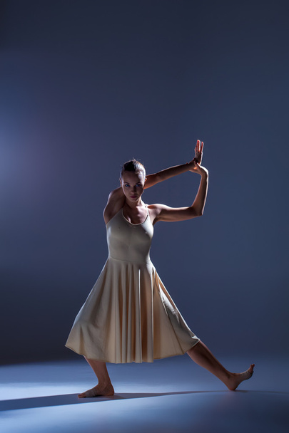 Young beautiful dancer in beige dress dancing on gray background - Φωτογραφία, εικόνα
