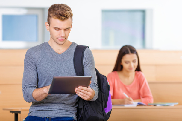 Estudiante apoyado en el escritorio y usando la tableta
. - Foto, imagen