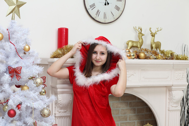 The girl in a suit of Santa Claus against a fireplace about a fu - Fotoğraf, Görsel