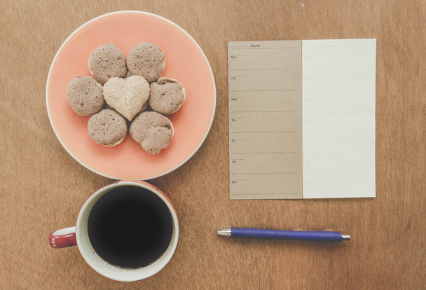 Memoria notebook vuoto e penna blu con caffè e biscotti su sfondo di legno - Vintage Filter Effect
 - Foto, immagini