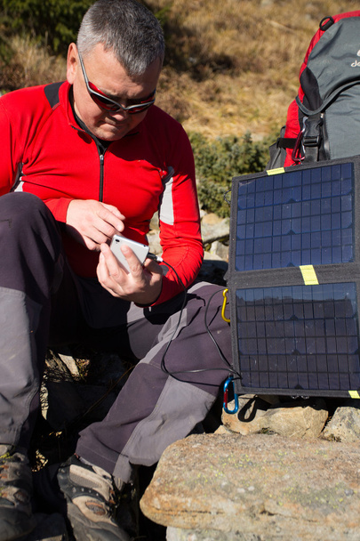 The solar panel attached to the tent. The man sitting next to mobile phone charges from the sun. - 写真・画像