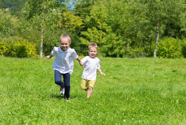Ευτυχισμένη χαρούμενη παιδιά τρέχει στο γρασίδι - Φωτογραφία, εικόνα