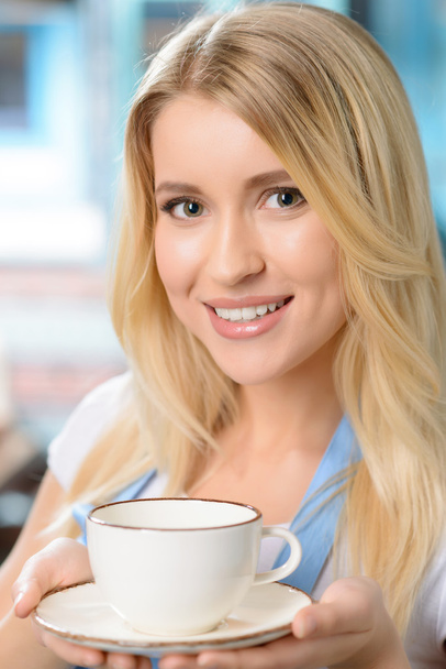Pleasant waitress holding cup - Фото, изображение