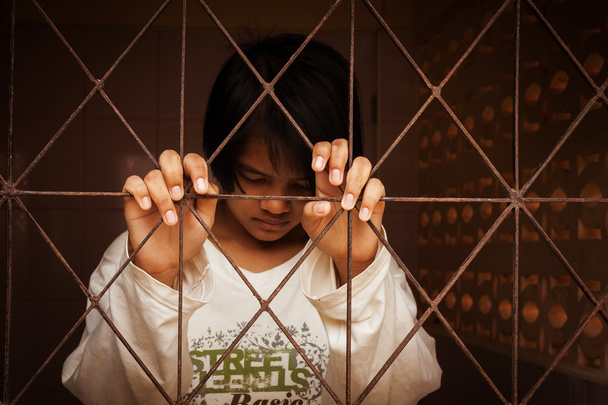дівчина сумно стоїть один за в'язницею
 - Фото, зображення