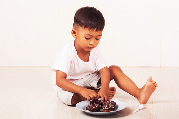 malý chlapec jíst čokoládový dort v místnosti - Fotografie, Obrázek