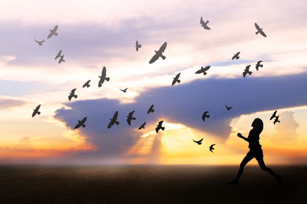Girl feeling freedom on field during sunrise, birds flying around - 写真・画像