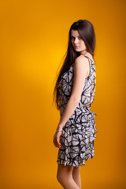 Young woman in dress on yellow background - Фото, изображение