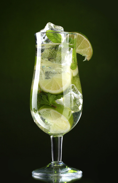 Glass of cocktail with lime and mint on green background - 写真・画像