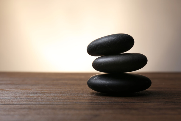 Black pebbles on wooden table - Φωτογραφία, εικόνα