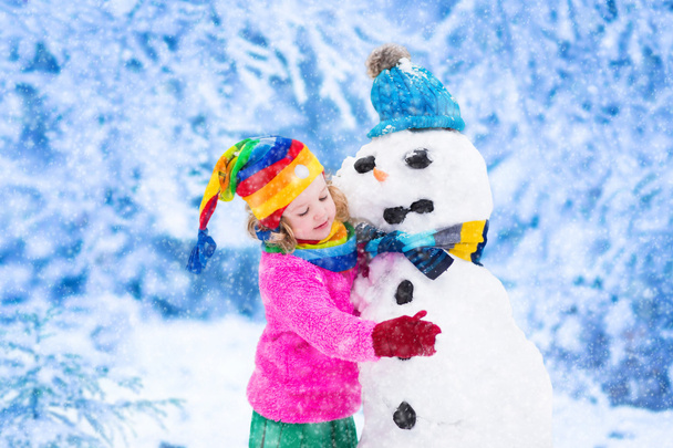 Malá holčička budování muž sněhu v zimě - Fotografie, Obrázek