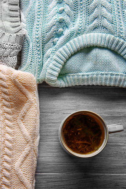 Mug of tea and warm clothes on wooden background - Foto, Bild
