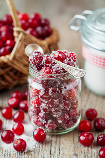 Cranberries in glass jar, basket with berries and sugar bowl - Photo, image