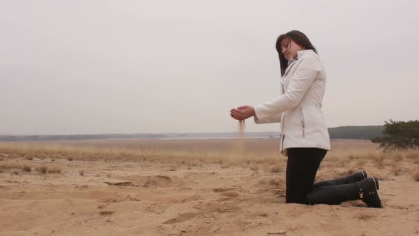 nő térdel és dob homok ősz hideg természet - Felvétel, videó