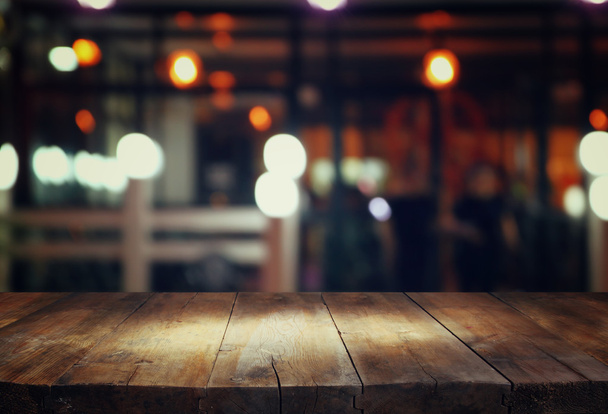 image of wooden table in front of abstract blurred background of resturant lights. - Foto, immagini