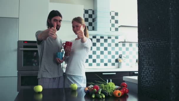 jonge gelukkige paar staande op de keuken in de ochtend duimen opdagen - Video