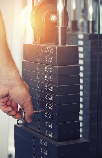 Ręka mężczyzny regulacji wagi w maszyny ćwiczeń w siłowni - Zdjęcie, obraz