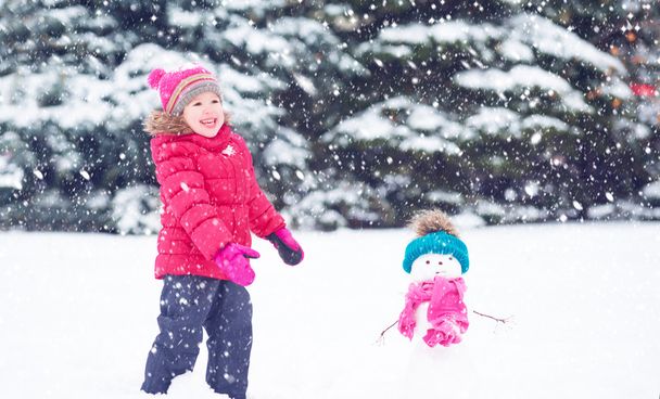 冬の散歩に雪だるまと幸せな子供女の子 - 写真・画像
