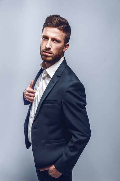 Studio shot of a stylish man in elegant suit, gray background, isolate - Foto, afbeelding