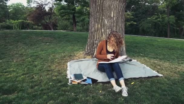 female student with a notebook in park slow motion - Кадры, видео