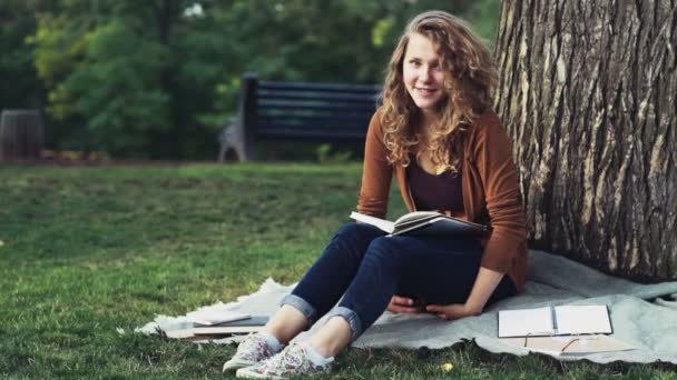 portrait of a happy female student sitting in the park slow motion - Footage, Video