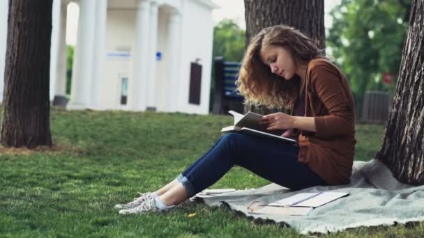 női hallgató olvasó park lassítva a fa alatt - Felvétel, videó