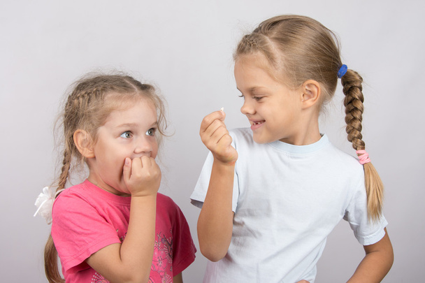 Menina de quatro anos com horror olha para o dente perdido em sua mão uma menina de seis anos
 - Foto, Imagem
