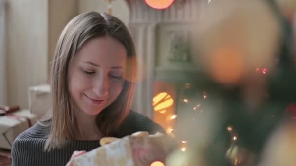Fiatal nő, ajándék karácsonyfa előtt - Felvétel, videó