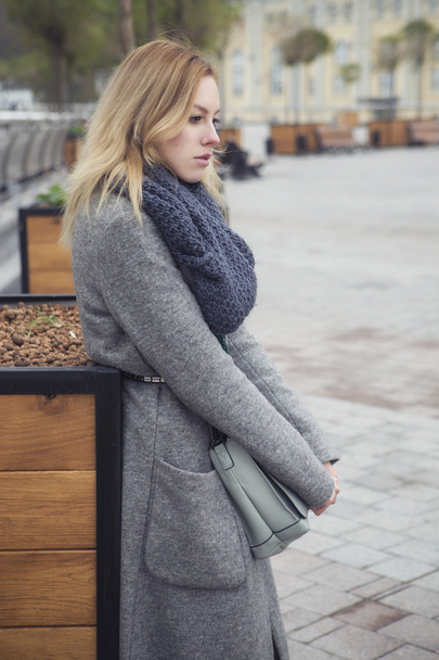Beautiful blonde young caucasian woman in grey coat and scarf wa - Фото, зображення