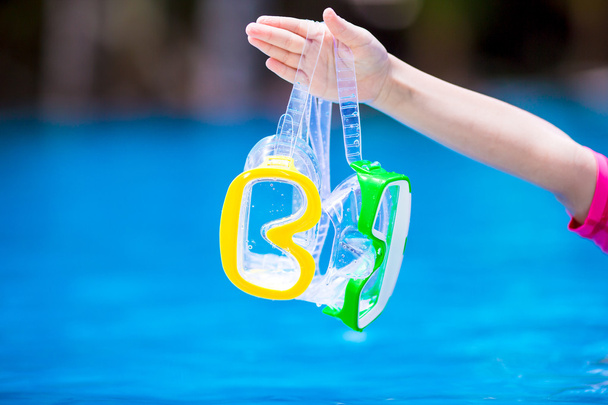 Две мокрые маски для акваланга в детской руке возле бассейна
 - Фото, изображение