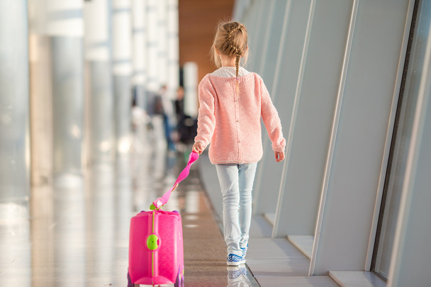 Imádnivaló kislány a reptéren, a poggyászával a beszállásra várva. - Fotó, kép