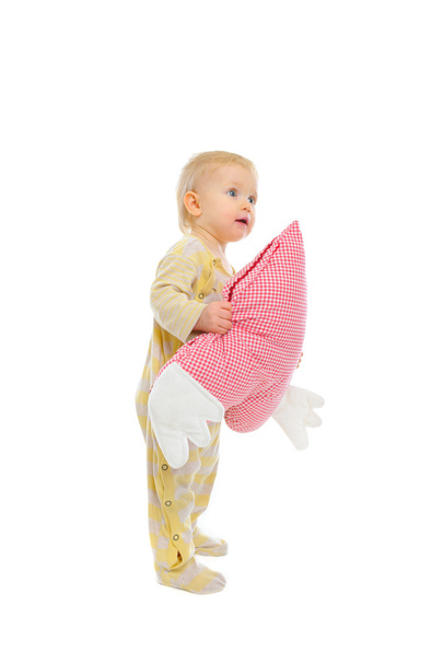 Interested baby standing with heart shaped pillow and looking in - Foto, Bild