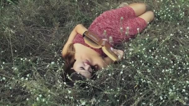 νεαρή γυναίκα γεννά στα λουλουδιών τομέων και διαβάζει ένα βιβλίο αργή κίνηση - Πλάνα, βίντεο