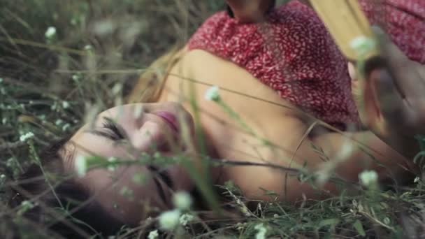 молода жінка лежить у польових квітах і читає книгу повільний рух
 - Кадри, відео