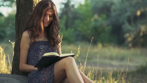 jonge vrouw leest een boek in bos slow motion - Video