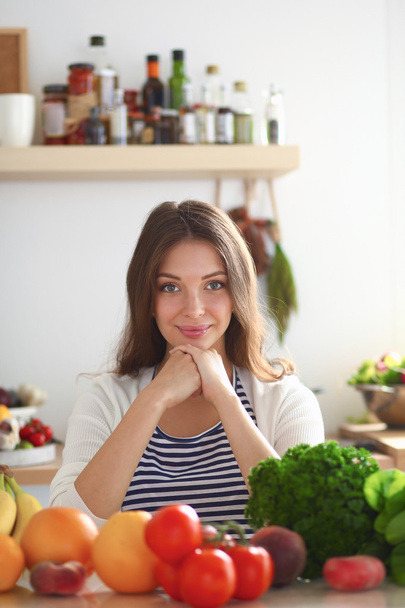 Junge Frau steht neben Schreibtisch in der Küche - Foto, Bild