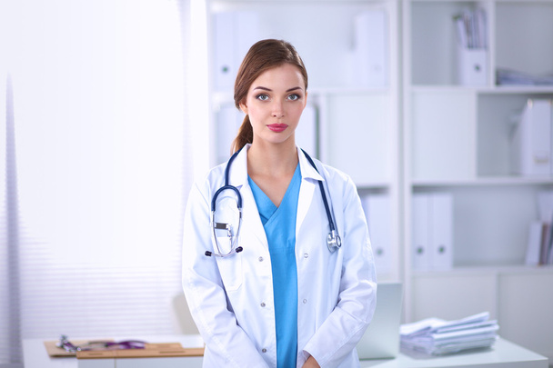 Portrait of young woman doctor with white coat standing in hospital - Foto, imagen